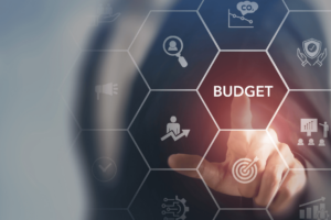 Main pointant l’hexagone « BUDGET » sur une interface numérique stylisée, illustrant les étapes du rachat de crédit dans un contexte financier et de gestion.