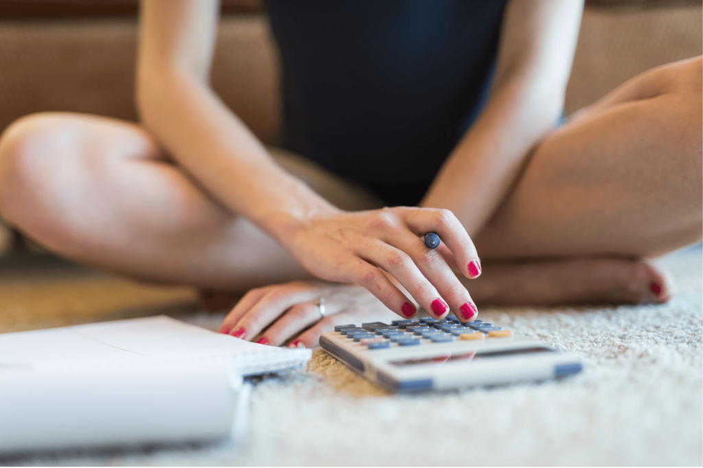 Personne assise en tailleur utilisant une calculatrice et un cahier, symbolisant l'étude de la possibilité d'emprunter sans son conjoint.