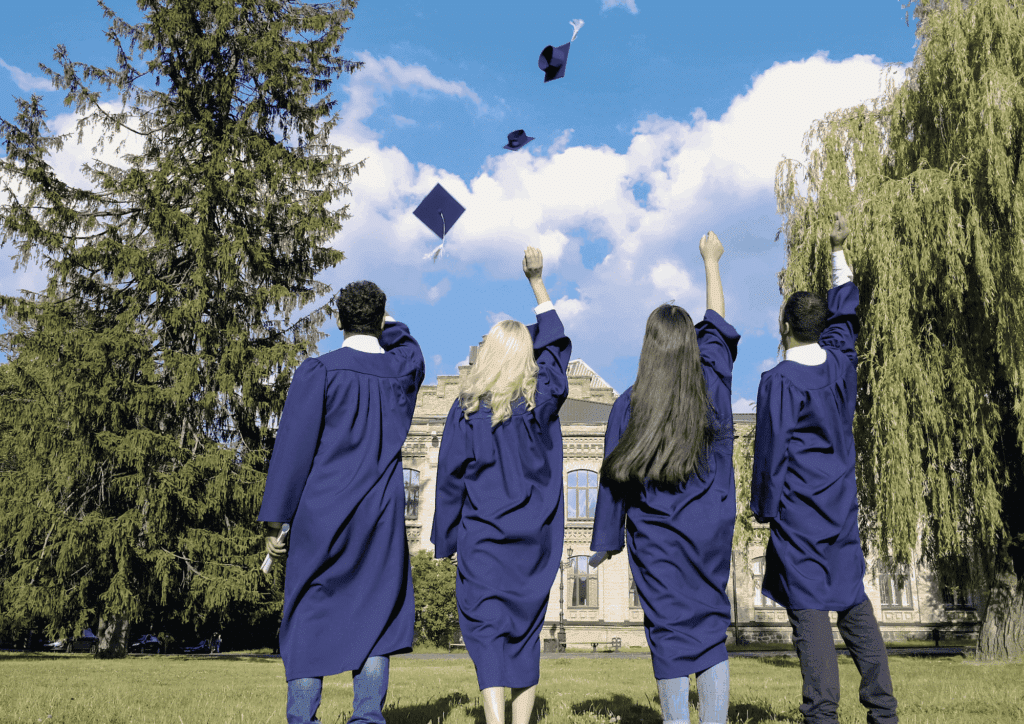Quatre étudiants diplômés, vêtus de toges et de toques, lancent leurs toques en l'air, symbolisant l'achèvement de leurs études supérieures, souvent financées par un prêt de trésorerie hypothécaire.