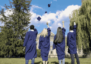 Quatre étudiants diplômés, vêtus de toges et de toques, lancent leurs toques en l'air, symbolisant l'achèvement de leurs études supérieures, souvent financées par un prêt de trésorerie hypothécaire.