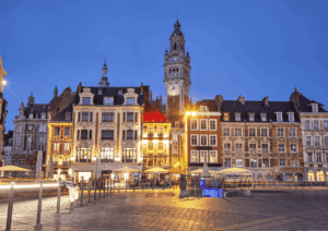 La Grand'Place de Lille au crépuscule, avec la Chambre de Commerce et d'Industrie illuminée, un cadre urbain typique du Nord de la France où l'on peut envisager un rachat de crédit.
