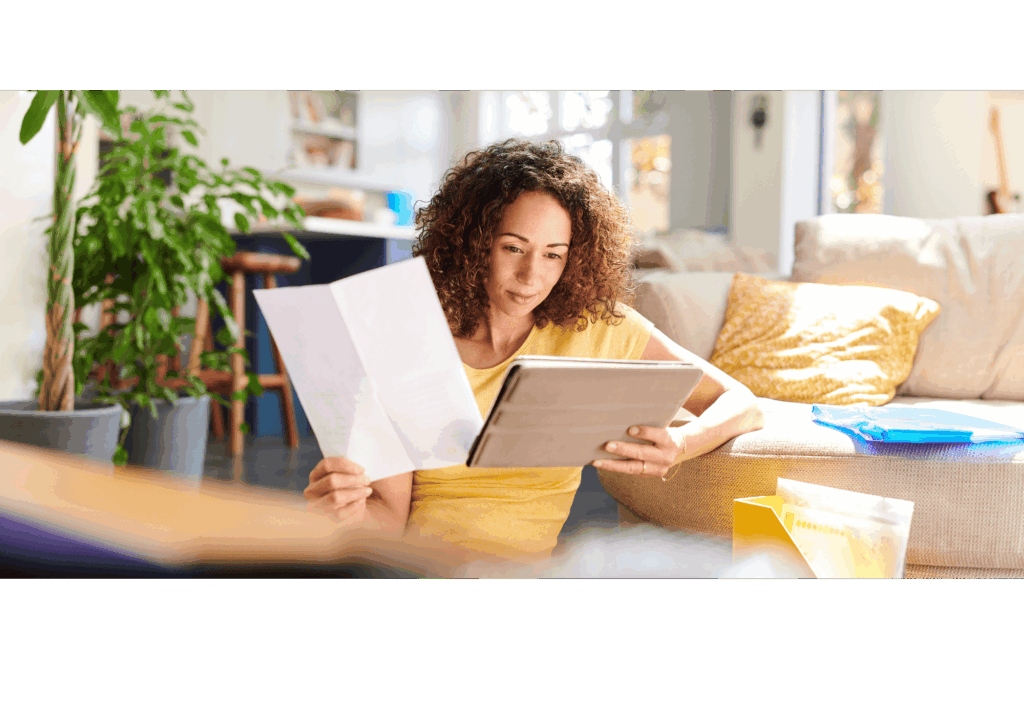 Femme gérant ses finances personnelles à la maison, consultant des documents et une tablette, illustrant le processus de réflexion avant un rachat de crédit.