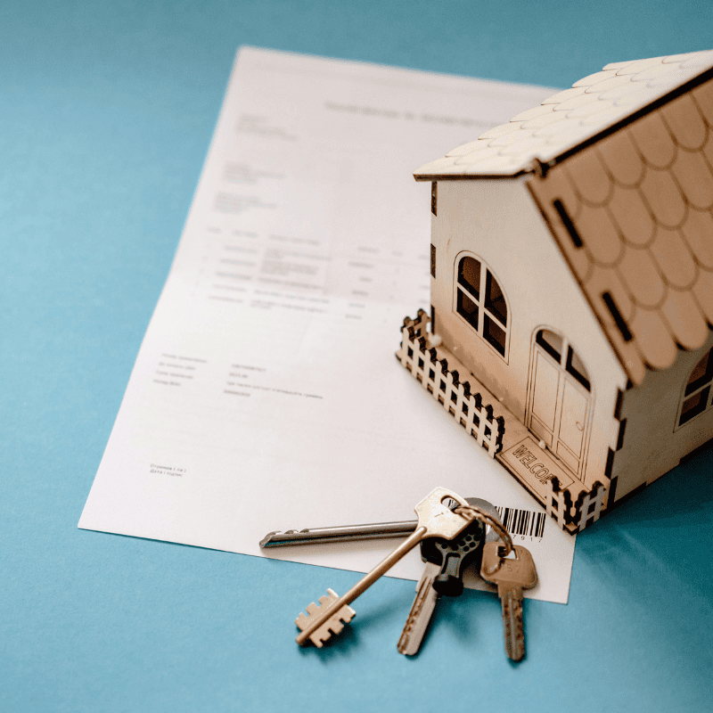 Maison miniature et ses clés posés sur une table bleu sur des documents symbolisant le simulateur prêt trésorerie hypothécaire