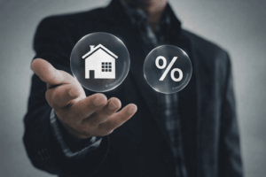 Homme en costume présentant une maison et un symbole pourcentage pour illustrer 5 conseils pour obtenir le meilleur taux immobilier
