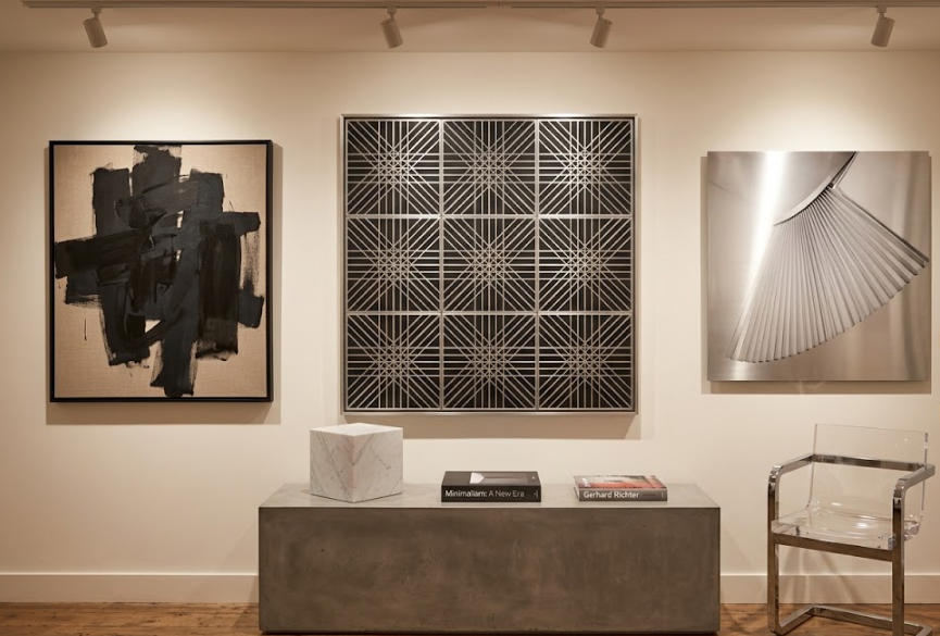 Photographie d'une collection d'art, présentant une sculpture murale géométrique d'OP-Art, une peinture abstraite en noir et blanc de grand format et une photographie conceptuelle en métal poli.